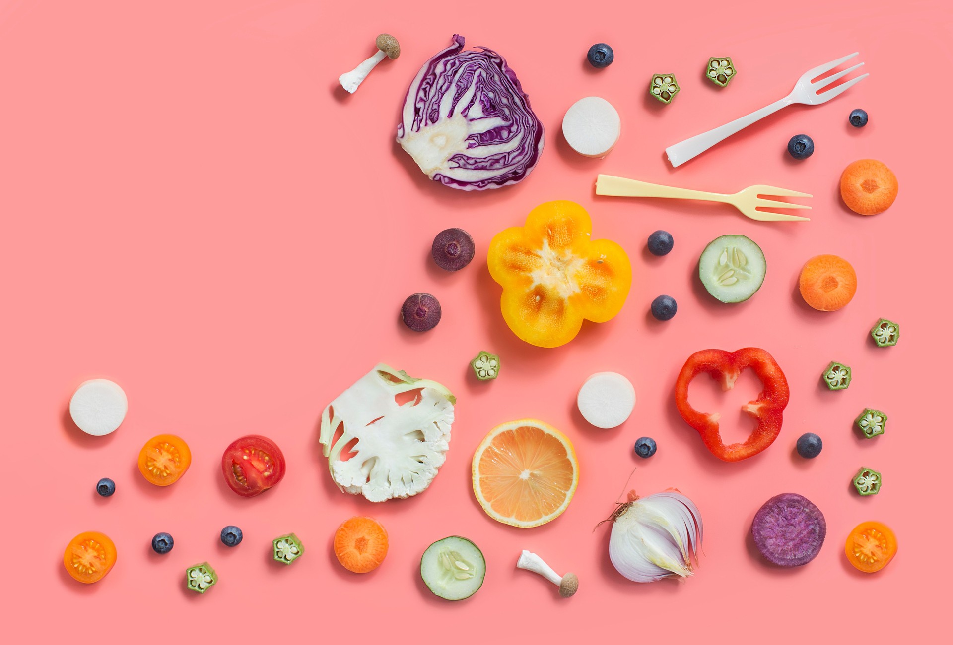 Colourful flat lay assorted sliced vegan food on pastel colour background.